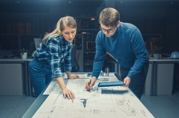 Two people looking at a blueprint over a table